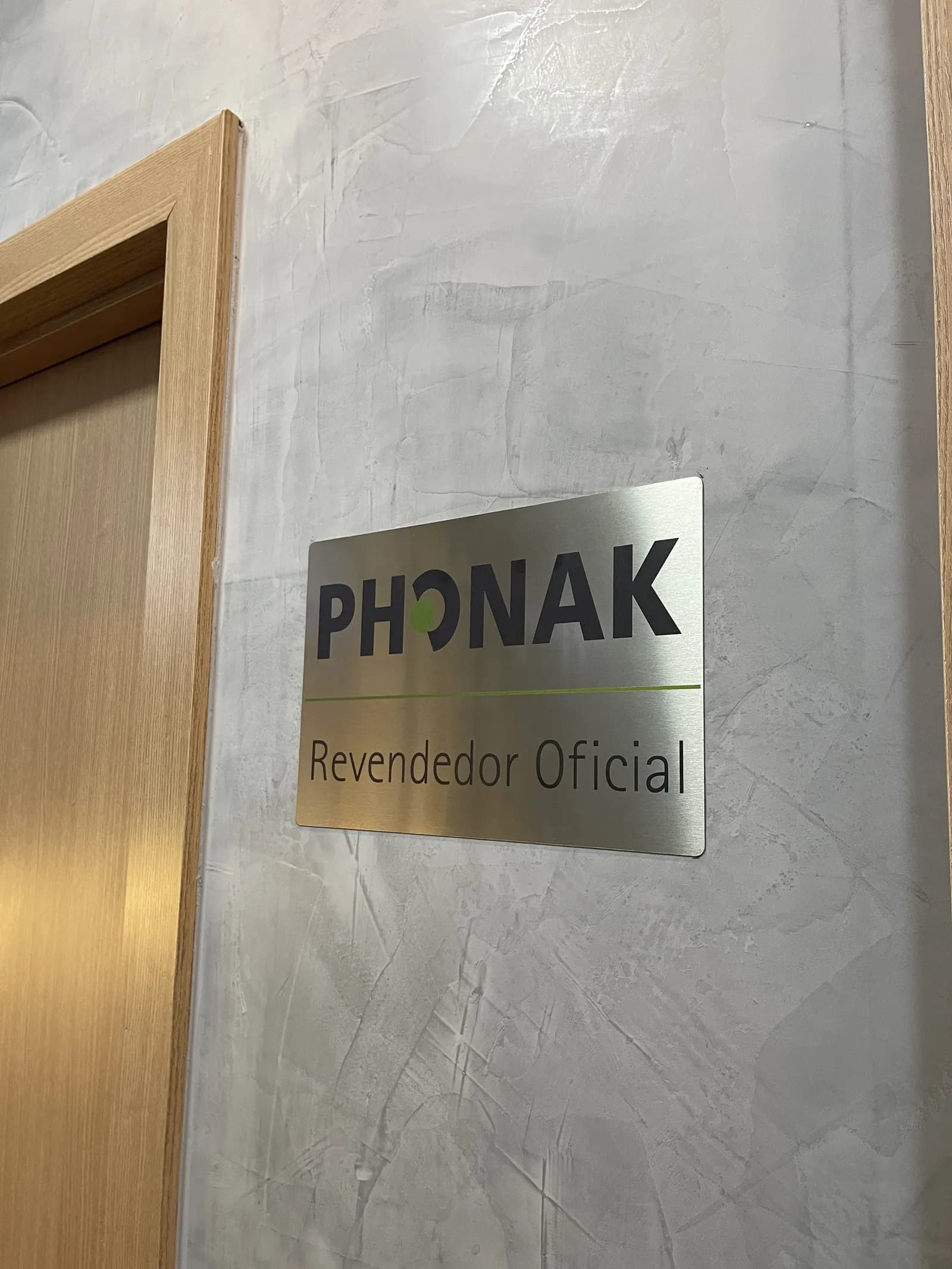 Placa de revendedor oficial Phonak na parede da clínica